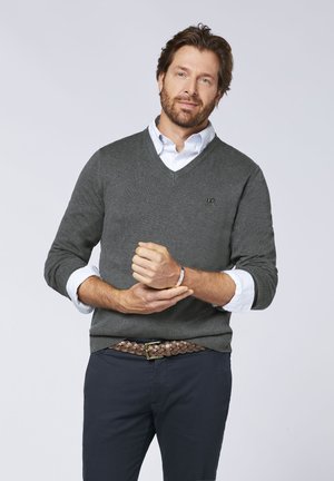 Gray v-neck sweater layered over a light blue striped collared shirt. Features long sleeves and a textured knit. Brown braided belt.