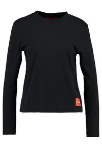 T-shirt noir à manches longues en coton ; avec un col rond et une petite étiquette logo orange en bas à gauche. Texture lisse, design ajusté.