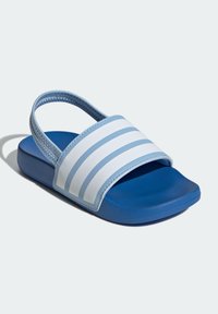 Blå halksandaler i gummi med stängd tå. De har ett brett vitt spänne med ljusblå ränder och en strukturerad övre kant.