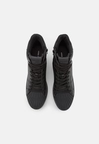 Black high-top sneakers with textured rubber soles, curved toe caps, and front zipper. Features logo on tongue and flat laces.