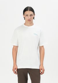 White cotton t-shirt with short sleeves and a round neck. Features light blue text graphic on the left side of the chest.