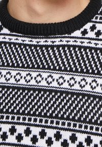 Czarnobiały sweter z dzianiny z geometrycznymi wzorami, okrągłym dekoltem i ściągaczami na rękawach. Tekstura jest gruba i przytulna.