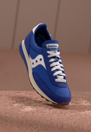 Plavacipele snubom od antilopa i kože, bijelim akcentima, teksturiranim vezicama i zakrivljenim potplatom. Ima "Saucony" oznaku na jeziku.