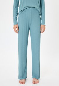 Conjunto de loungewear de canalé en azul claro que incluye una camiseta de manga larga y pantalones de largo completo con dobladillos acampanados. Textura suave, cinturilla elástica.