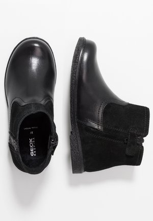 Paar zwarte enkellaarsjes met gladde leren neuskap en suède zijkanten, voorzien van ritssluitingen aan de zijkant en gegoten rubberen zolen met textuur.