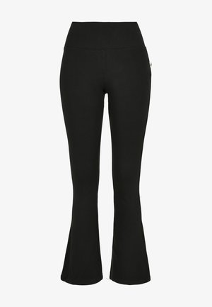 Pantalon de yoga noir taille haute avec jambes évasées, tissu lisse et petite étiquette logo blanche sur le côté droit.