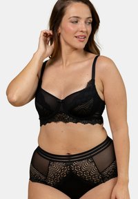 Bralette en dentelle noire avec bretelles réglables, présentant des bords festonnés et un motif floral. Culottes taille haute noires avec des panneaux transparents.