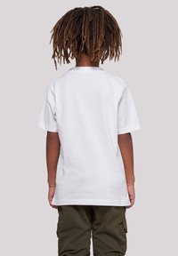 White cotton t-shirt with short sleeves, a rounded neckline, and a relaxed fit, worn with green cargo pants.