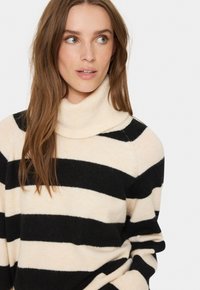 Cremfarbener Rollkragenpullover mit schwarzen horizontalen Streifen. Hergestellt aus weichem, strukturiertem Stoff. Verfügt über eine lockere Passform und einen gerippten Kragen.