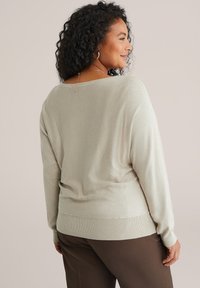 Világosszürke, hosszú ujjú pulóver, laza fazonnal, bordázott mandzsettákkal és szegéllyel, enyhén redőzött hátrésze, puha, textúrált anyagból készült.