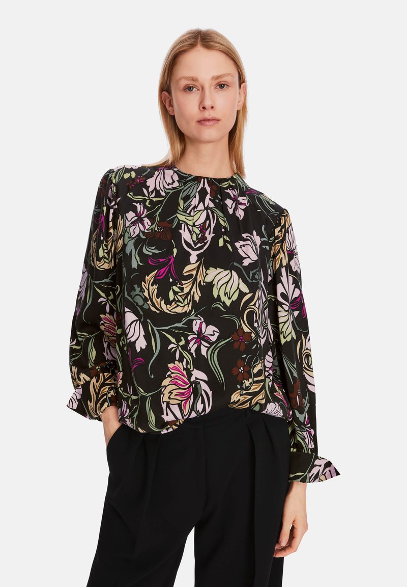 Schwarze Bluse mit floralem Muster in Pink, Grün und Creme. Sie verfügt über einen runden Halsausschnitt und lange Ärmel mit gerafften cuffs.