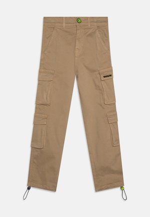 Tan cargo pants with multiple pockets, adjustable cuffs, and a black logo on the thigh. Features a green button detail. Twill fabric.