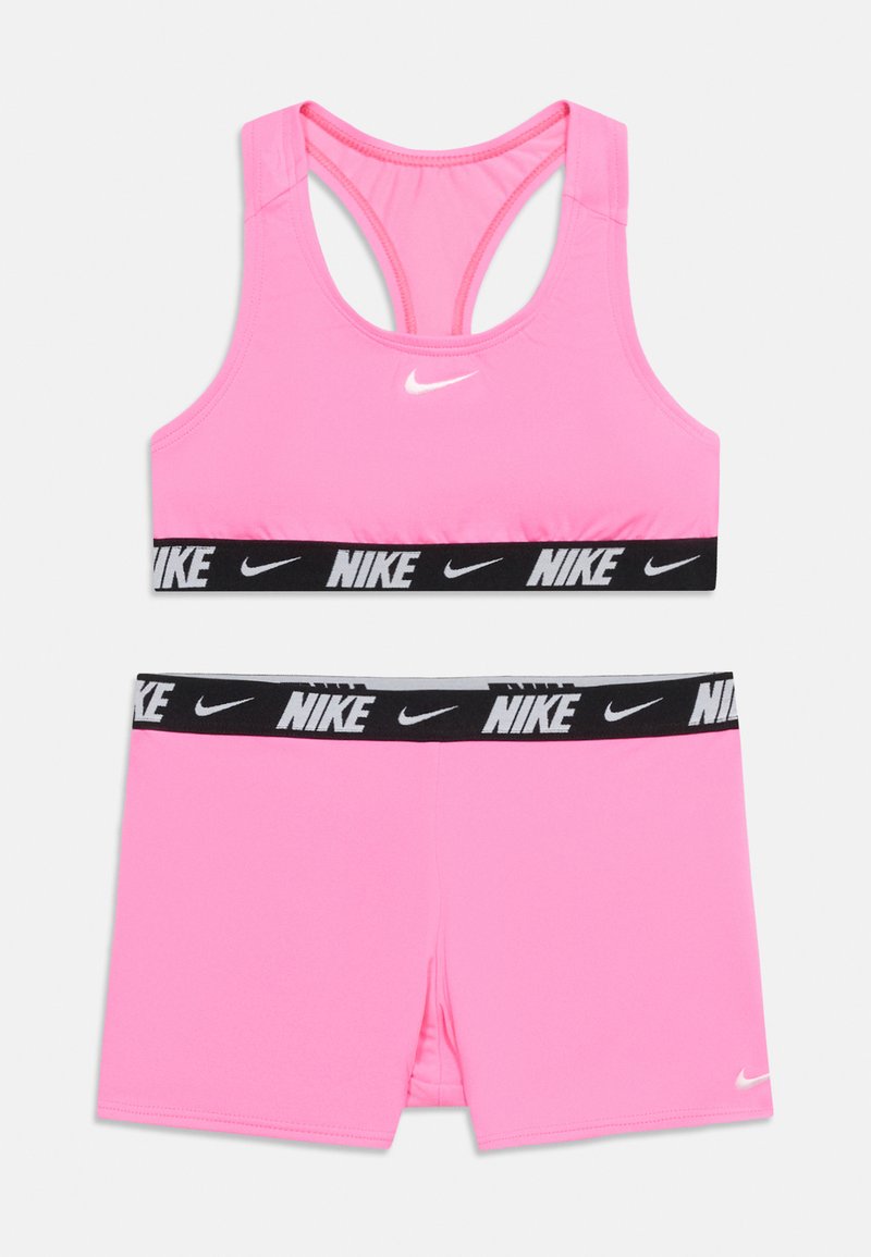 Ρόζ αθλητικό σουτιέν Nike και αντίστοιχα σορτς με μαύρες ελαστικές ταινίες που φέρουν λευκά λογότυπα και σήματα Nike.