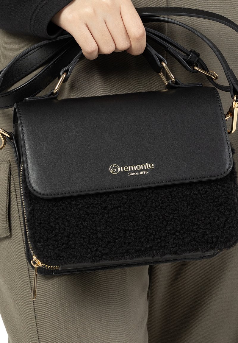 Black handbag featuring a smooth upper material and a textured, fuzzy lower panel; gold hardware accents; detachable shoulder straps.