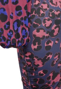 Gros plan d’un tissu avec un imprimé léopard violet et noir irrégulier sur la manche et un imprimé léopard rose et noir sur le corps bleu foncé.