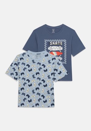 Dvě dětská trička s krátkým rukávem: jedno modré s motivy ovladače videohry a blesků, druhé námořnicky modré s grafikou skateboardu a nápisem "SKATE".