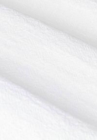 Close-up of layered white cotton and terry cloth fabric with visible weave and texture details.