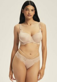 Nude lingerie set featuring a padded bra with lace trim and a matching brief with floral lace accents and crisscross straps.