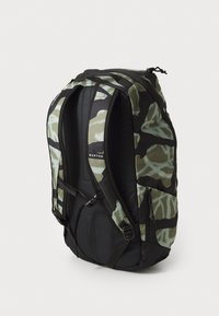 Camo-patterned Burton backpack with padded shoulder straps, side zipper pocket, and a black back panel, shown standing upright.