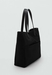 Sac tote noir avec deux poignées en cuir, corps en tissu, forme rectangulaire, doté d'une grande poche avant et d'un design épuré et minimal.