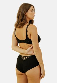 Ensemble de lingerie noire comprenant un soutien-gorge en dentelle et un culotte taille haute. Le soutien-gorge possède des bretelles réglables et un dos décoratif.