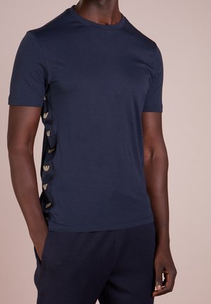 T-shirt in cotone blu navy con maniche corte, caratterizzato da accenti del logo dorati lungo le cuciture laterali, scollo rotondo e taglio aderente.