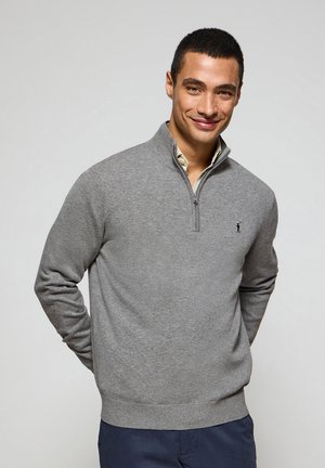 Grauer Reißverschluss-Pullover aus einem weichen Strickstoff, mit einem gerippten Saum und Bündchen, und einem kleinen gestickten Logo auf der Brust.
