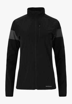 Schwarze Softshell-Jacke mit durchgehendem Reißverschluss, hohem Kragen, Brusttasche und reflektierenden Akzenten an den Ärmeln. Glatte Textur und taillierte Passform.