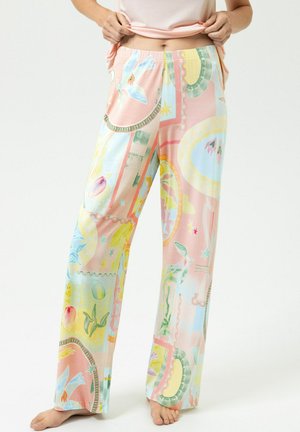 Personne portant un pantalon ample de couleur pastel avec des motifs floraux et géométriques abstraits, pieds nus, relevant un haut rose pour montrer la ceinture.