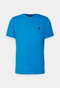 Blå bomuld T-shirt med rund halsudskæring, korte ærmer og et lille rødt broderet logo på venstre bryst. Glat tekstur.