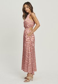 Abito maxi in fantasia houndstooth rosso e crema, design senza maniche con tagli laterali, dotato di tasche e una consistenza fluida.