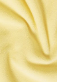 Tessuto giallo chiaro con una superficie morbida e testurizzata, che mostra sottili pieghe e grinze, indicando flessibilità e caduta.