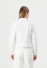 Hvit denimjakke med skreddersydd passform, krage og knappede mansjetter, med en ren design og minimale sømdetaljer.