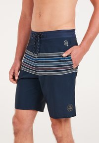 Marine zwembroek met horizontaal streepjespatroon in tinten blauw, grijs en bordeaux. Voorzien van een trekkoord in de taille en een zijzak.