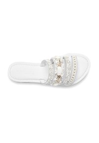 White sandal featuring multiple decorative straps with beaded and shell accents, flat sole, and smooth leather texture.