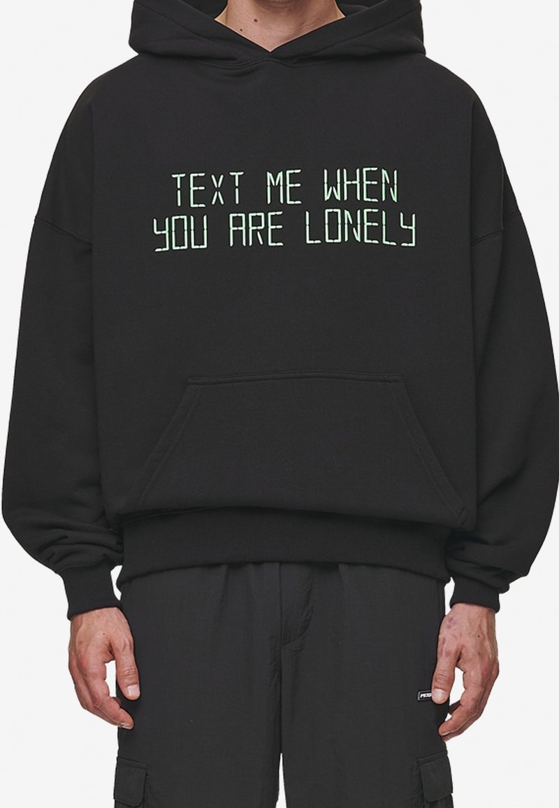Black hooded sweatshirt featuring green text that reads "TEXT ME WHEN YOU ARE LONELY." Made of soft material with a spacious pocket.