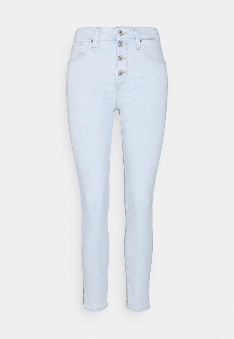 Jeans de cintura alta en azul claro con cierre frontal de cinco botones, ajuste slim, ligero desgaste en el tobillo y sin bolsillos visibles.