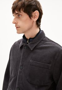 Grau gestreifte Cordjacke mit Kragen, Knöpfen auf der Vorderseite und einer Brusttasche. Verfügt über ein strukturiertes Muster und ein körpernahes Design.