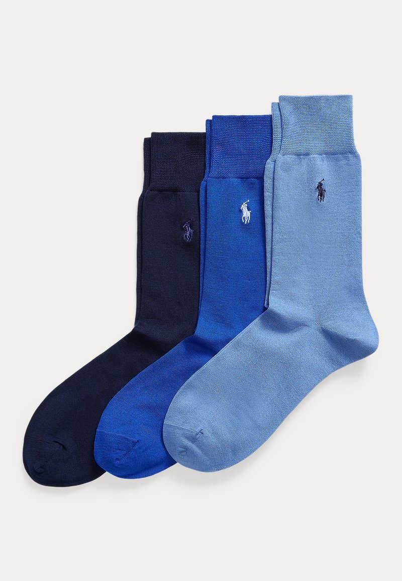Trys sulankstytų kelninių kojinių poros tamsiai mėlynos, karališkos mėlynos ir šviesiai mėlynos spalvos su Polo Ralph Lauren logotipu ant čiurnos, išdėstytos šalia viena kitos.