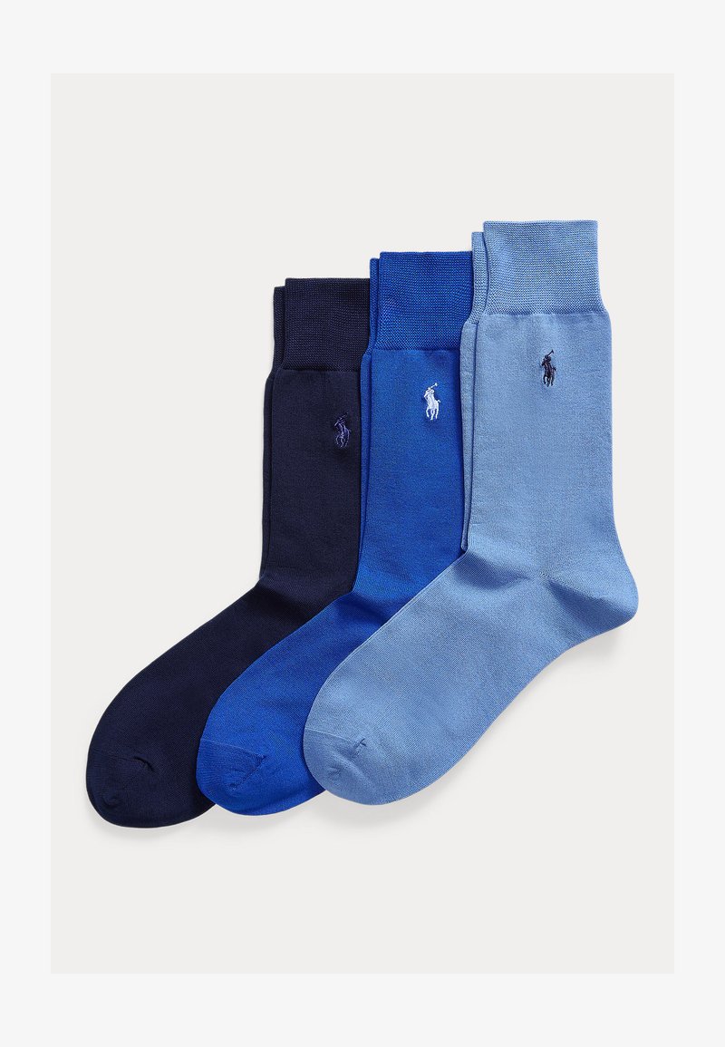 Trys sulankstytų kelninių kojinių poros tamsiai mėlynos, karališkos mėlynos ir šviesiai mėlynos spalvos su Polo Ralph Lauren logotipu ant čiurnos, išdėstytos šalia viena kitos.