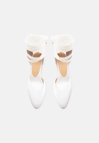 Λευκά επίπεδα εσπαντρίγιες με κλειστή μύτη και κορδόνια για δέσιμο στον αστράγαλο, σε θέαση από πάνω σε απλές φόντο.