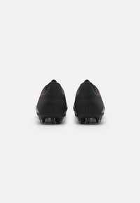Bottes de football noires avec une tige texturée, une forme aérodynamique et des crampons moulés. Présentent une accent rouge sur les côtés et un talon bas.