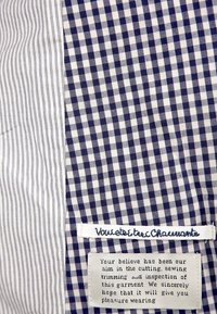 Niebieska i biała tkanina w kratkę w stylu gingham z teksturowanym paskiem; zawiera metkę z kursywą oraz etykietę z instrukcją pielęgnacji.