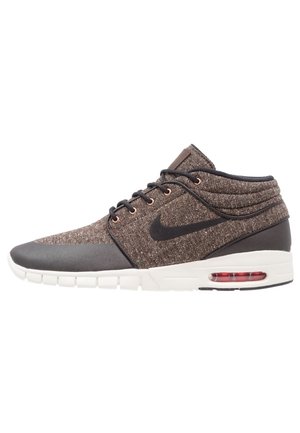 Baskets Nike montantes marron et noires avec tige en tissu, logo Swoosh noir, semelle blanche et coussinet d'air visible au talon, vues de profil.