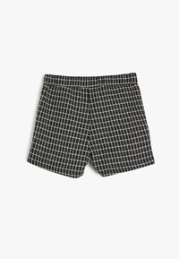 Shorts à carreaux noir et blanc avec une taille élastique, présentant un motif de grille carrée et un tissu doux et texturé.