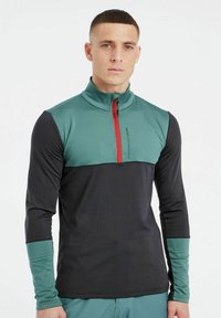 Herren Langarmoberteil in Grün und Schwarz, mit hohem Kragen, einem Viertel-Reißverschluss mit rotem Akzent und kontrastierenden Ärmelbündchen.