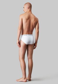 Culottes blanches en coton avec une taille élastique affichant le logo "Calvin Klein". Texture lisse, coupe ajustée et design classique de culotte.