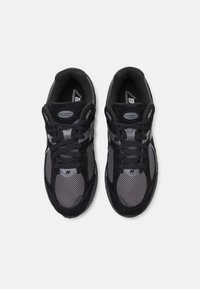 Harmaat ja mustat urheilukengät, joissa on verkkokangas- ja mokkanahkatiemateriaaleja, nauhallinen muotoilu, pehmustettu kaulus ja korotettu pohja.