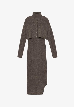 Adīta kleita ar augstu apkakli un saīsinātu virsējo slāni tumši pelēkā krāsā. Raksturīga ribota tekstūra un pogu aizdare priekšpusē. Asimetriska apakšmala.