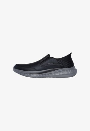 Zapatillas deportivas negras sin cordones con parte superior sintética suave, paneles laterales texturizados y suela de goma gris. Ligeras con un diseño contorneado.